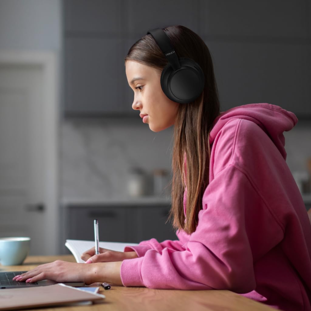 Person wearing headphones and using a laptop at a table in a kitchen.
