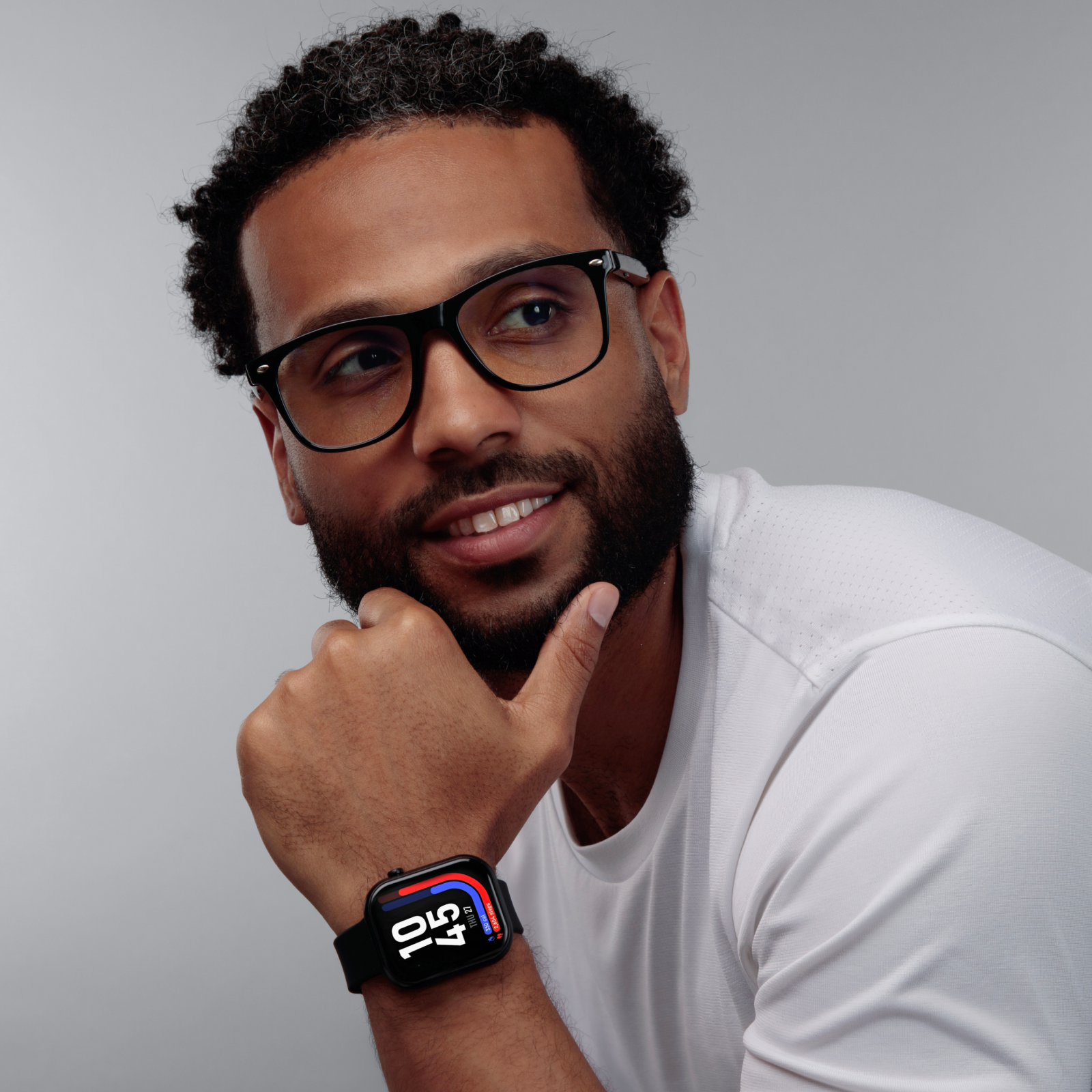 Man wearing a smartwatch with a white shirt on a gray background